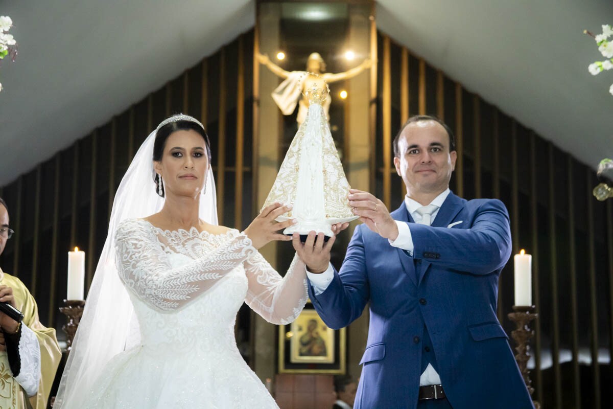 Anna e Eduardo seguram a imagem de Nossa Senhora no altar 